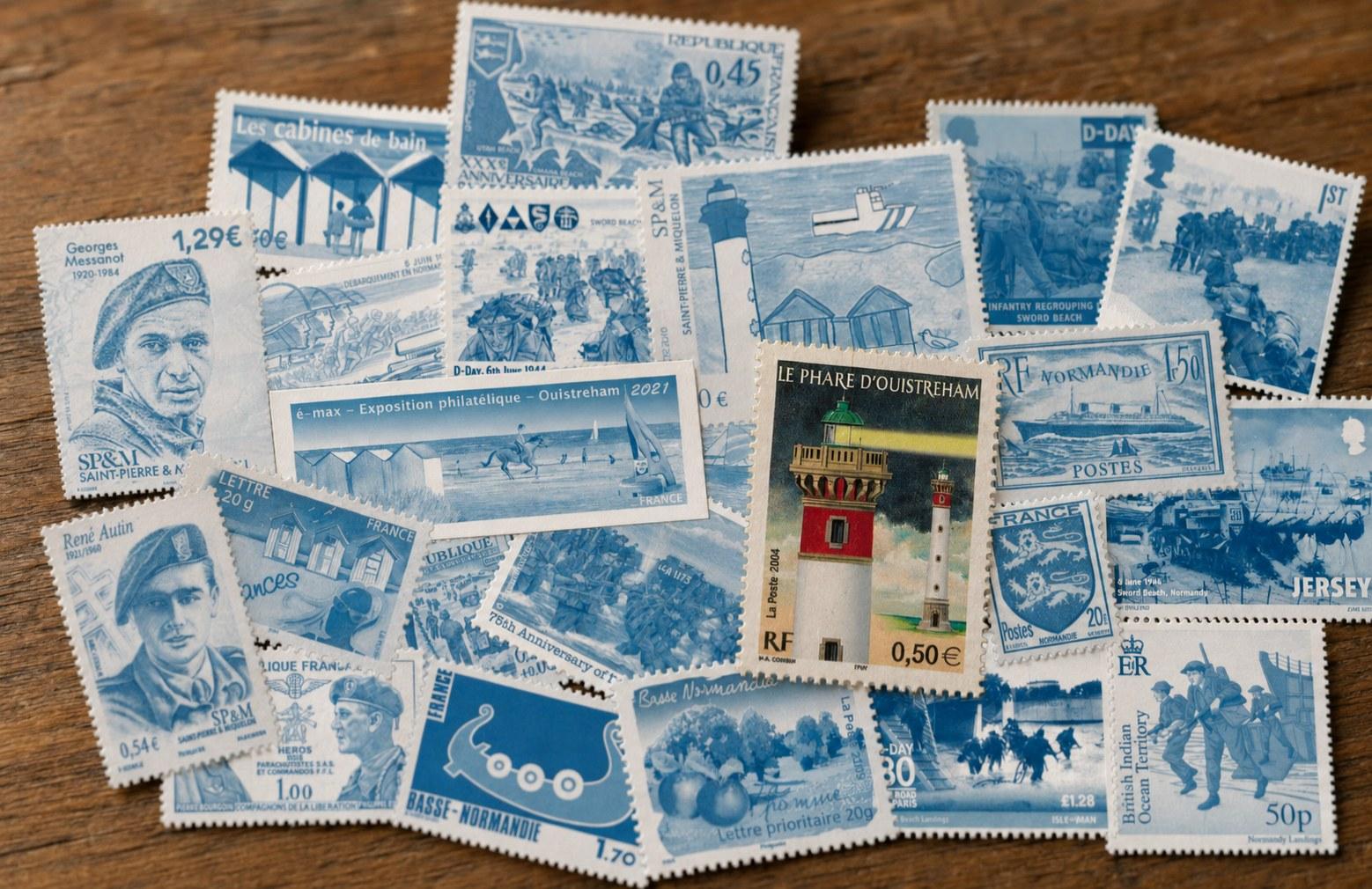 Composition de timbres virés en bleu — Sword Beach, les cabines de bain, le paquebot Normandie, le blason de Normandie — au centre desquels ressort, seul en couleur, « Le Phare d'Ouistreham » (La Poste, 2004)